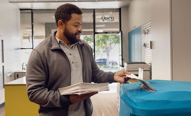 Man putting documents into The UPS Store Shredding bin