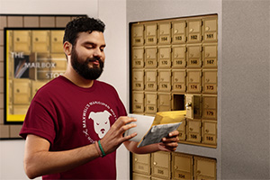 Male small business owner holding a stack of mail in front of The UPS Store mailboxes. 