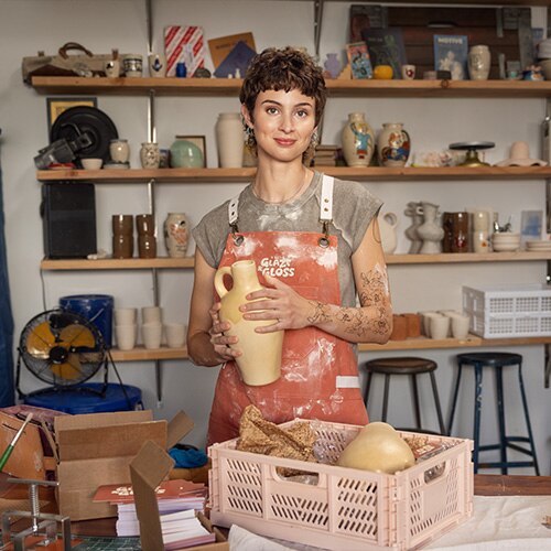 A woman holding pottery in a pottery studio.