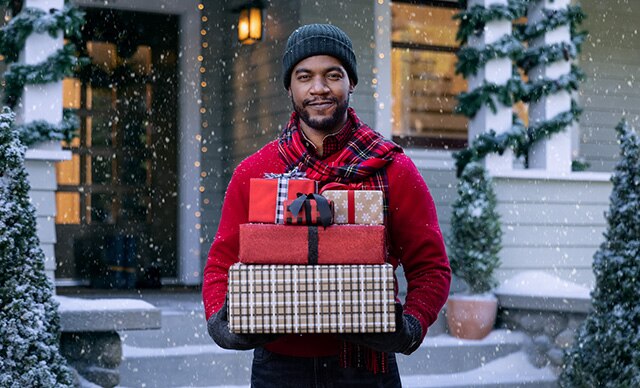 Man holding wrapped gifts outside in the snow